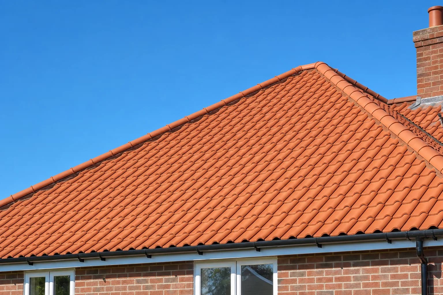 New terracotta clay tiled roof on a UK home with clean ridge tiles